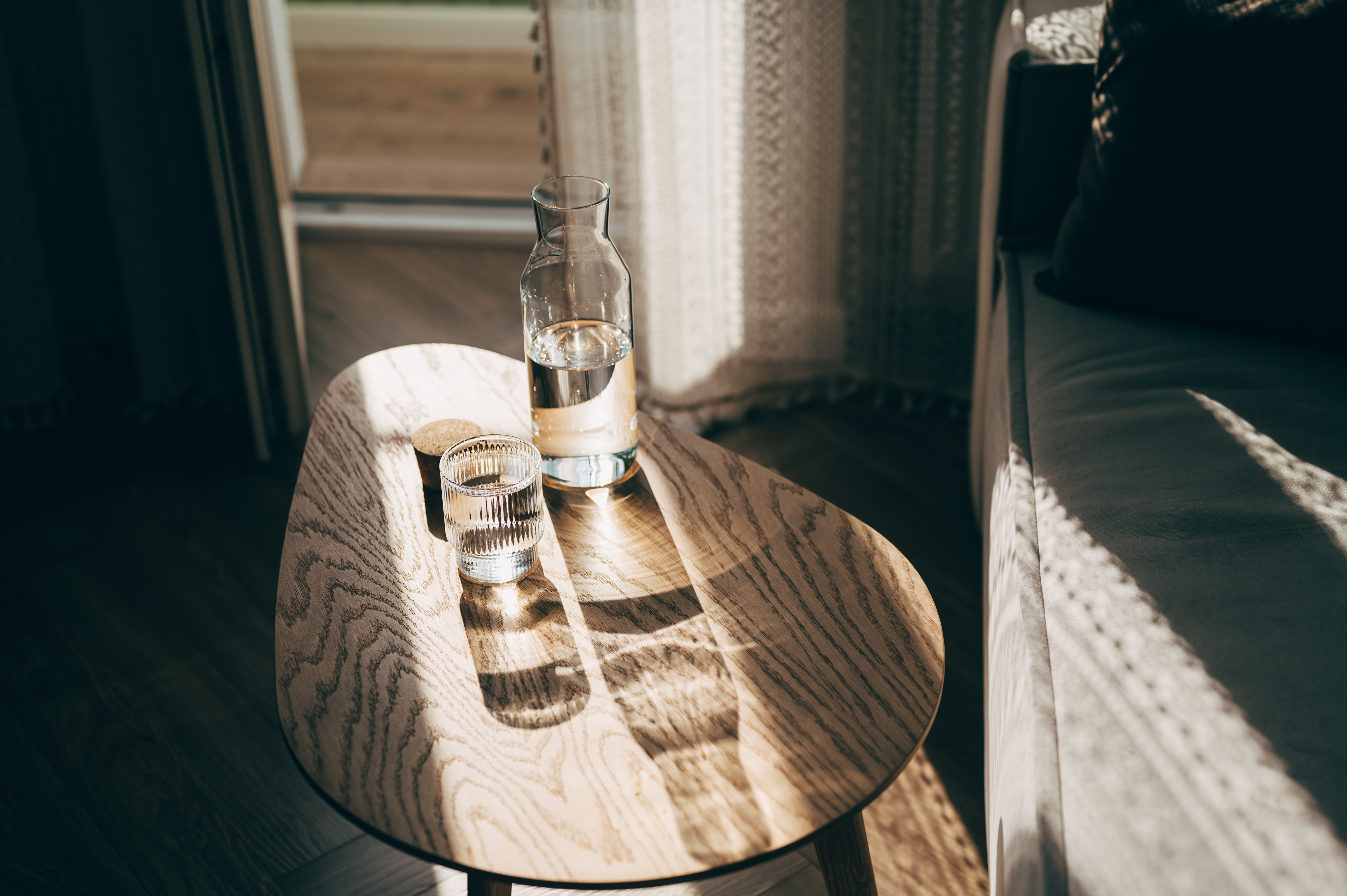 Wasserkaraffe und Glas auf einem Holztisch bei Sonnenlicht