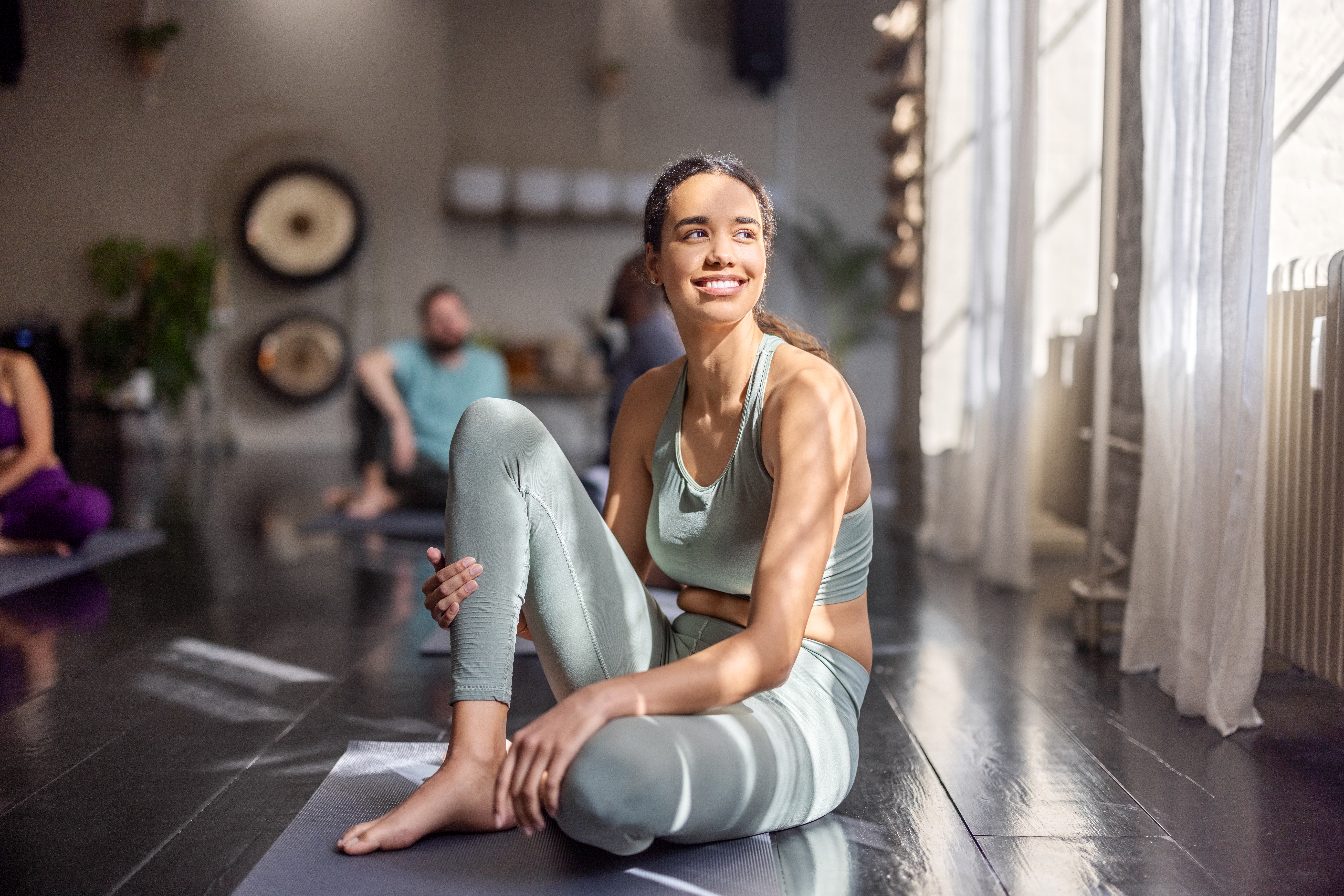 Frau auf einer Yogamatte in einem Kursraum